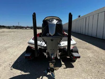 Slide: The Image of 2024 Blazer 650 Pro Tour boat, rear view, parked on gravel near a building. - 5