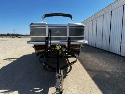 Slide: The Image of 2025 SunCatcher Select 322RC pontoon boat on trailer, parked near storage facility. - 2