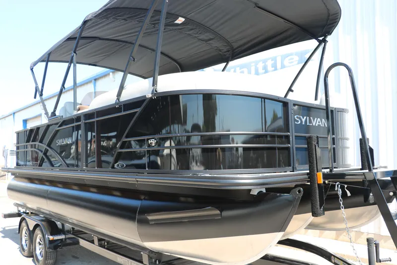 Slide: The Image of 2025 Sylvan Mirage X3 Party Fish pontoon boat with black canopy on trailer. - 13