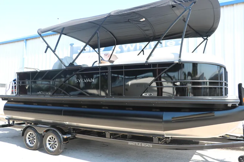 Slide: The Image of 2025 Sylvan Mirage X3 Party Fish pontoon boat with black canopy on trailer. - 14