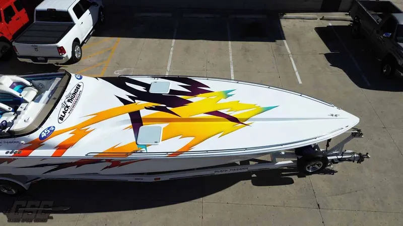 Slide: The Image of 2001 Black Thunder 43 GT Flat Deck boat with vibrant graphics, parked on a trailer. - 17
