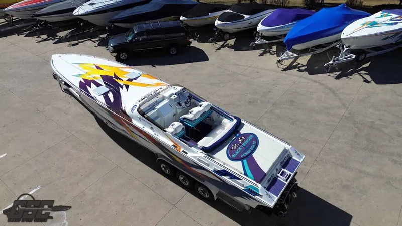 Slide: The Image of 2001 Black Thunder 43 GT Flat Deck boat with vibrant graphics, parked among other boats. - 23