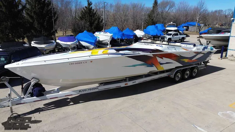 Slide: The Image of 2001 Black Thunder 43 GT Flat Deck boat on trailer, vibrant graphics, parked outdoors. - 28