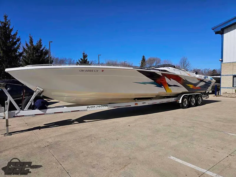 Slide: The Image of 2001 Black Thunder 43 GT Flat Deck boat on trailer, vibrant graphics, parked outdoors. - 30