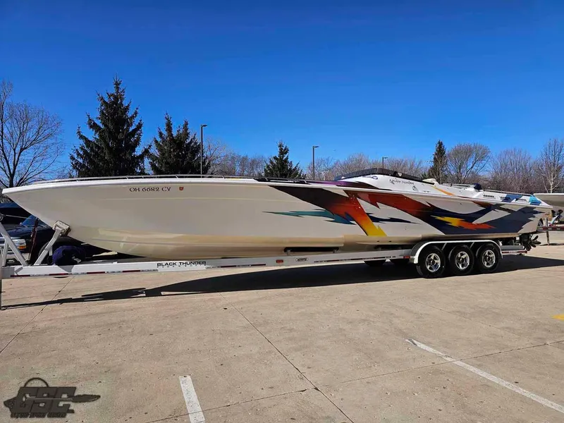 Slide: The Image of 2001 Black Thunder 43 GT Flat Deck boat on trailer, vibrant graphics, parked outdoors. - 31