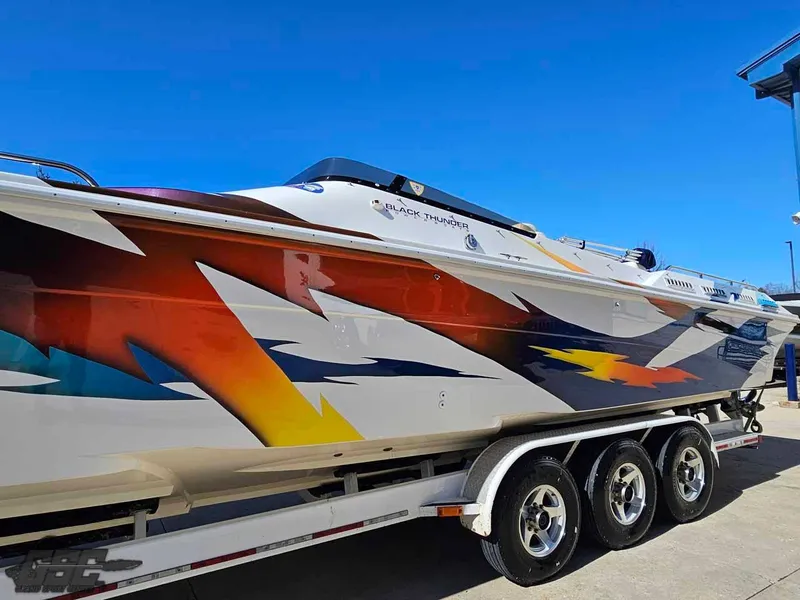 Slide: The Image of 2001 Black Thunder 43 GT Flat Deck boat with vibrant, colorful graphics on a trailer. - 35