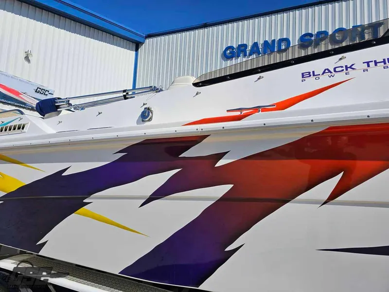 Slide: The Image of 2001 Black Thunder 43 GT Flat Deck boat with vibrant graphics at Grand Sport facility. - 5