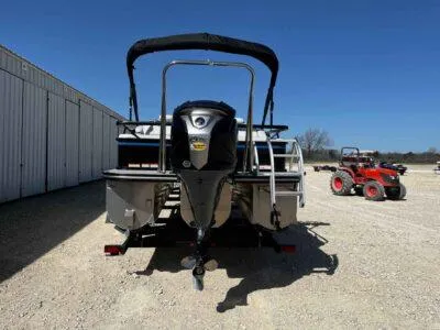 Slide: The Image of 2025 SunCatcher Select 322SS pontoon boat with outboard motor, parked near a red tractor. - 6