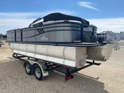 Slide: The Image of 2025 SunCatcher Select 322RC pontoon boat on a trailer, parked outdoors. - 2