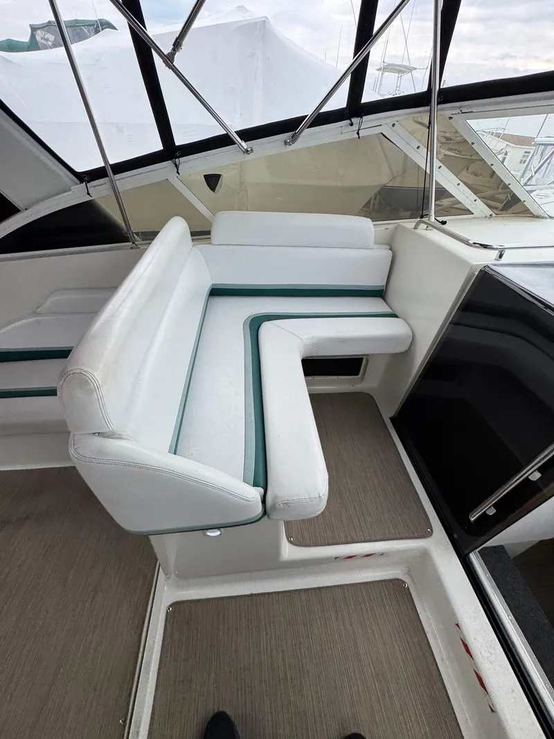Slide: The Image of 1995 Silverton Express boat interior with white and green cushioned seating. - 11