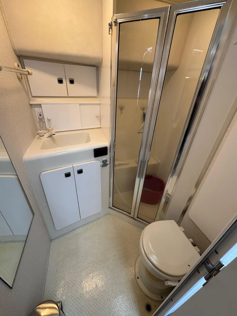 Slide: The Image of 1995 Silverton Express bathroom with shower, sink, and toilet in compact marine design. - 21