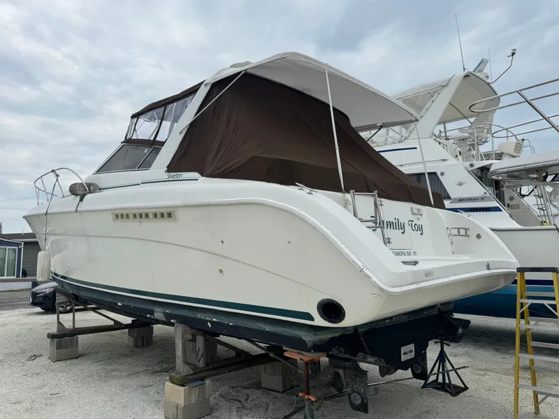 Slide: The Image of 1995 Silverton Express boat on dry dock, white hull, brown canopy, overcast sky. - 4