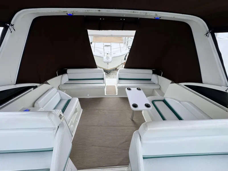 Slide: The Image of Interior of a 1995 Silverton Express boat with white seating and a central table. - 8
