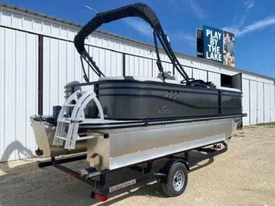 Slide: The Image of 2025 SunCatcher Select 320 RC pontoon boat on trailer, parked near a building. - 4