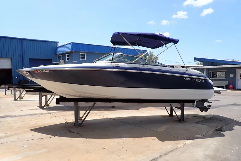 The Image of 2002 Cobalt 240 boat with blue canopy on a stand at a marina. - 0