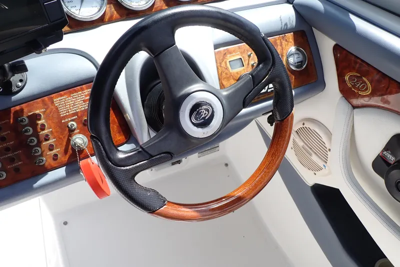 Slide: The Image of Steering wheel of a 2002 Cobalt 240 boat with wood accents and control panel. - 18