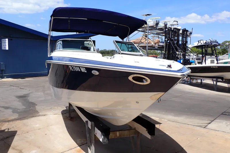 Slide: The Image of 2002 Cobalt 240 boat with blue canopy on a dock under clear skies. - 2