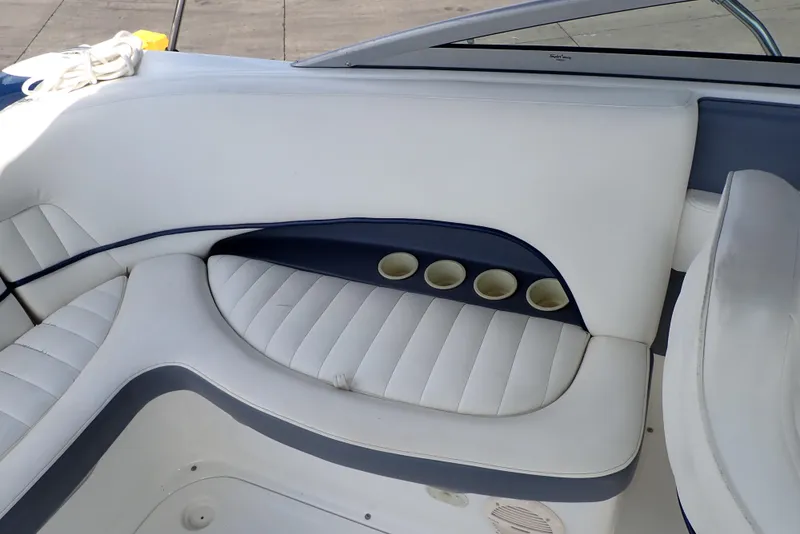 Slide: The Image of 2002 Cobalt 240 boat interior with white cushioned seating and cup holders. - 20