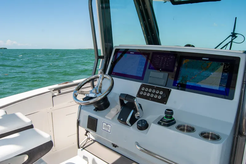 Slide: The Image of 2023 Crevalle 33 CSF boat dashboard with navigation screens and steering wheel. - 2