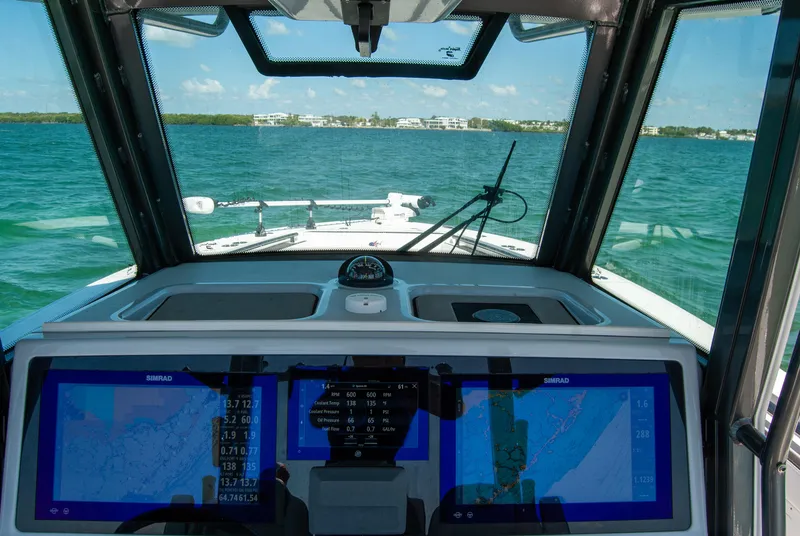 Slide: The Image of 2023 Crevalle 33 CSF boat cockpit with navigation screens, steering towards open water. - 20