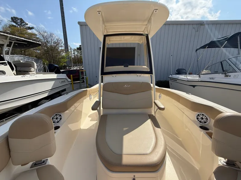 Slide: The Image of 2023 Scout 215 XSF boat interior with seating and console, docked outdoors. - 40