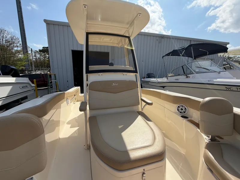 Slide: The Image of 2023 Scout 215 XSF boat interior with seating and console under a clear sky. - 41