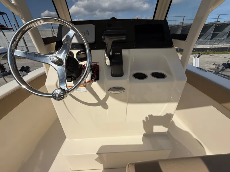 Slide: The Image of 2023 Scout 215 XSF boat helm with steering wheel and controls under sunny sky. - 45