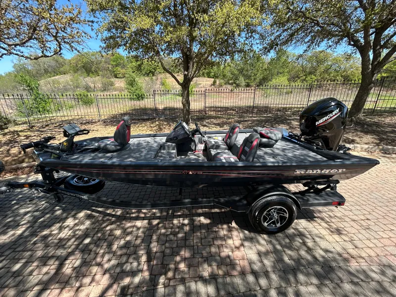 Slide: The Image of 2023 Ranger RT178 fishing boat on a trailer, parked outdoors under trees. - 47