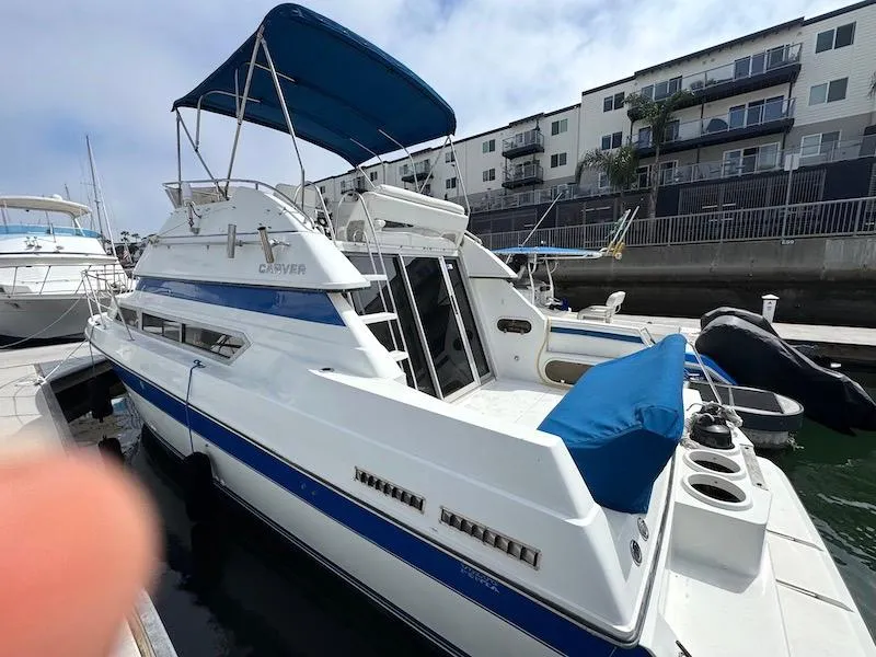 Slide: The Image of 1989 Carver 30 Santego boat docked, featuring blue accents and a canopy. - 3