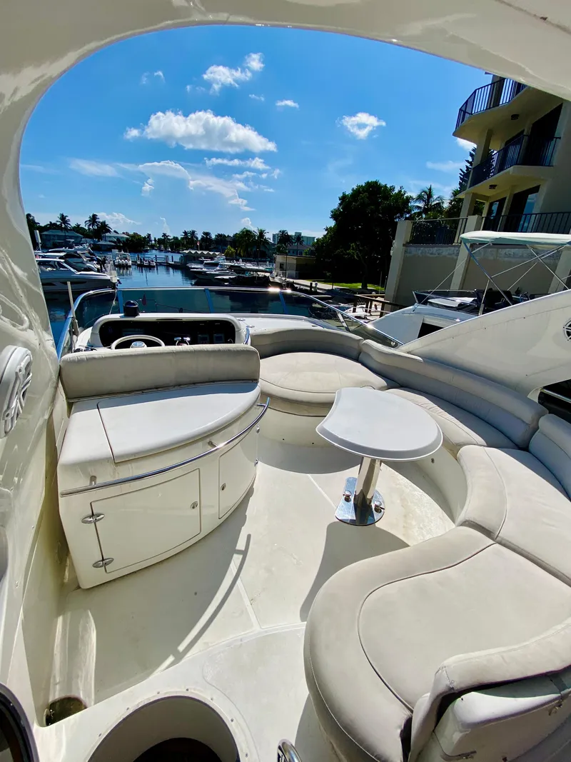 Slide: The Image of 2002 Azimut 55 yacht deck with seating, table, and marina view under blue sky. - 19