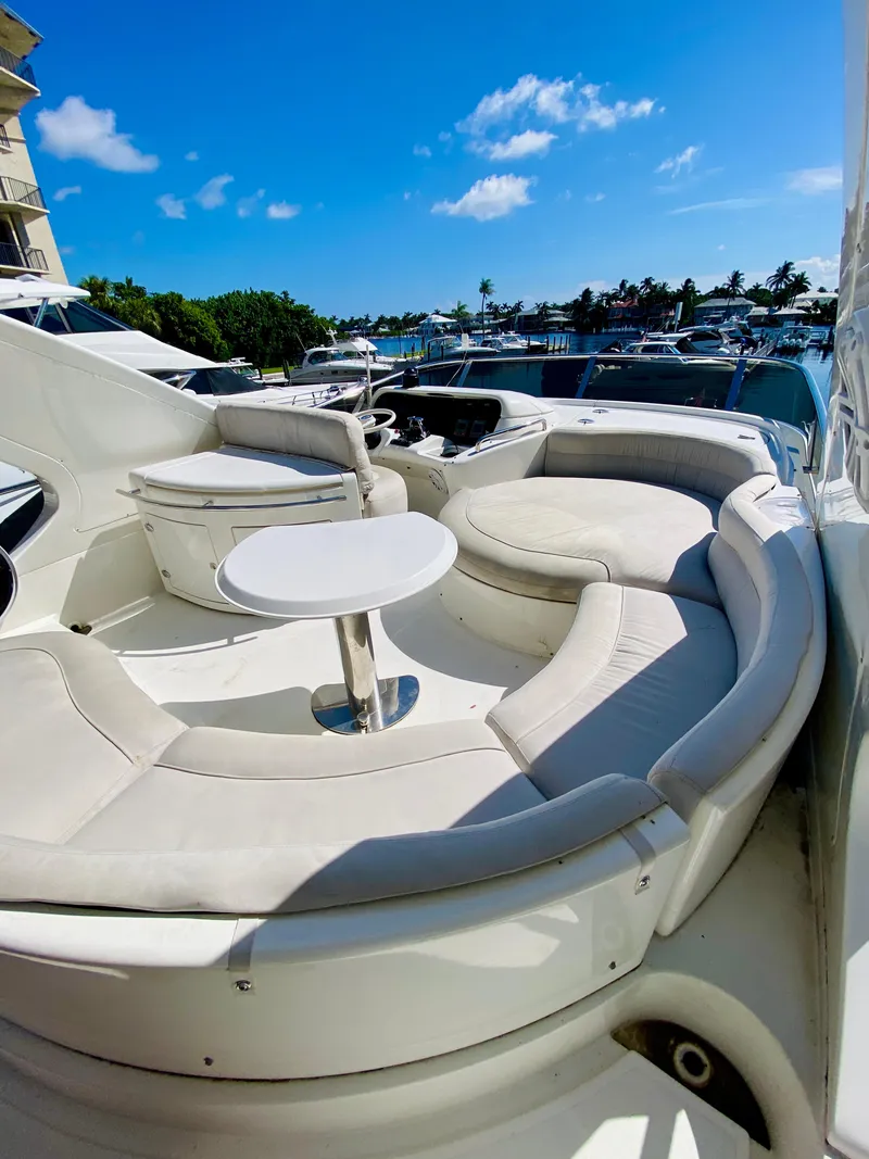 Slide: The Image of Luxurious 2002 Azimut 55 yacht with elegant seating area and table, docked under a clear blue sky. - 21