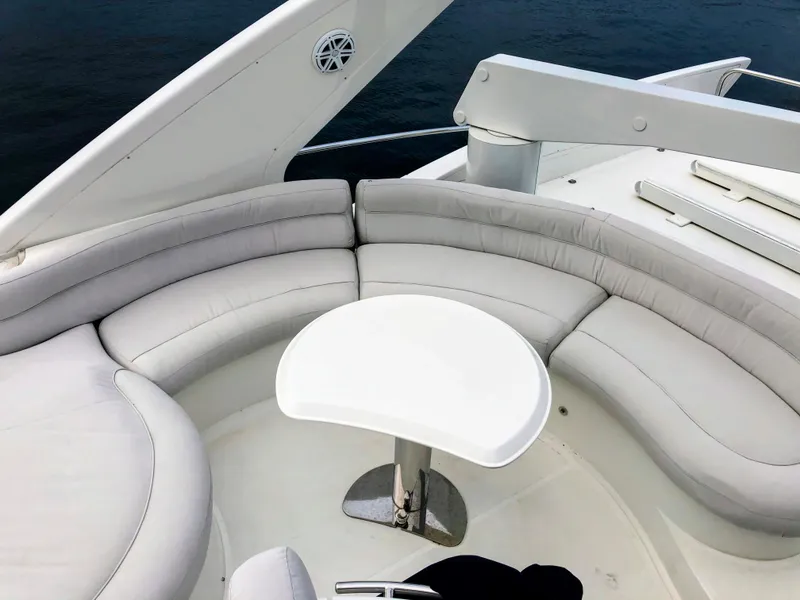 Slide: The Image of Luxurious seating area on 2002 Azimut 55 yacht, featuring white cushioned seats and table. - 23