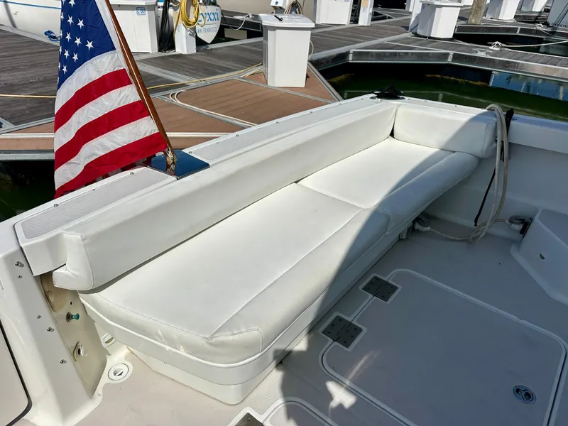 Slide: The Image of White seating area on a 2008 Back Cove 33 Express boat, docked with an American flag. - 15