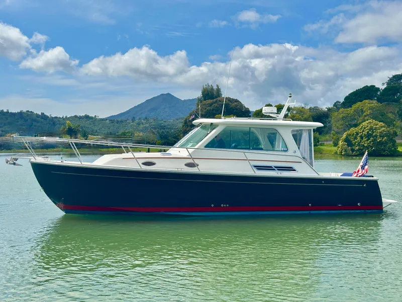 Slide: The Image of 2008 Back Cove 33 Express boat on calm water with scenic mountain backdrop. - 2