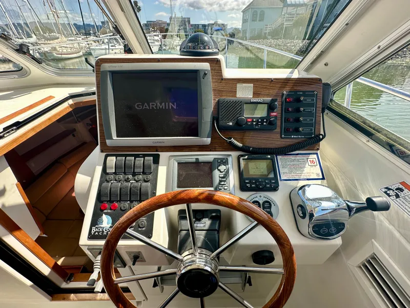 Slide: The Image of 2008 Back Cove 33 Express helm with Garmin navigation, wooden steering wheel, and control panel. - 25