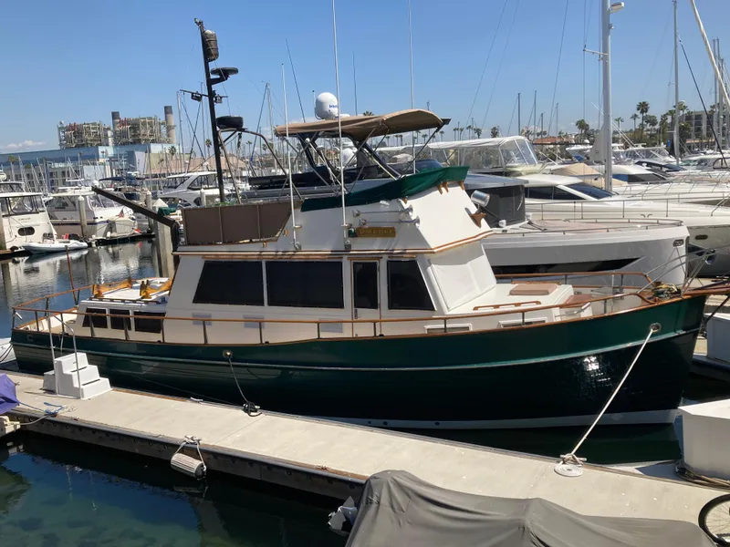 Slide: The Image of 1985 Grand Banks 42 Classic yacht docked at a marina, featuring a green hull and spacious deck. - 3