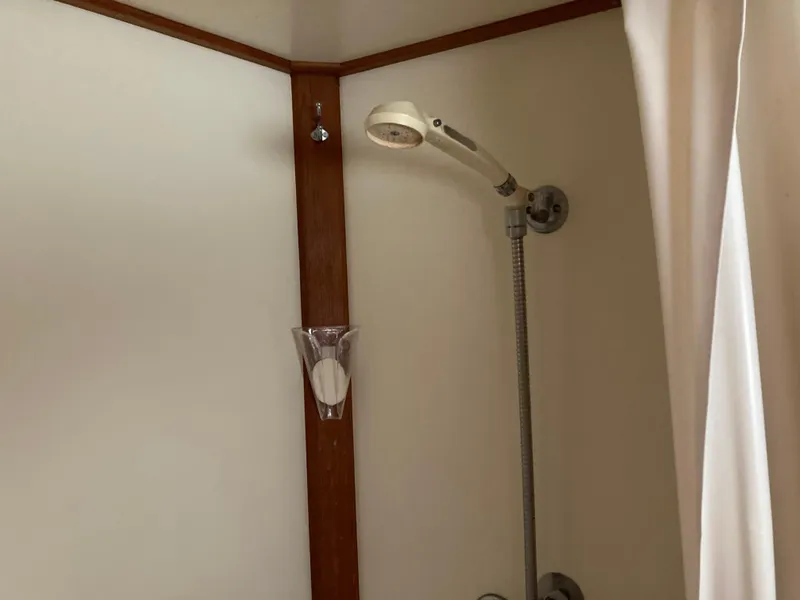 Slide: The Image of Shower area in 1985 Grand Banks 42 Classic boat, featuring a handheld showerhead and curtain. - 30