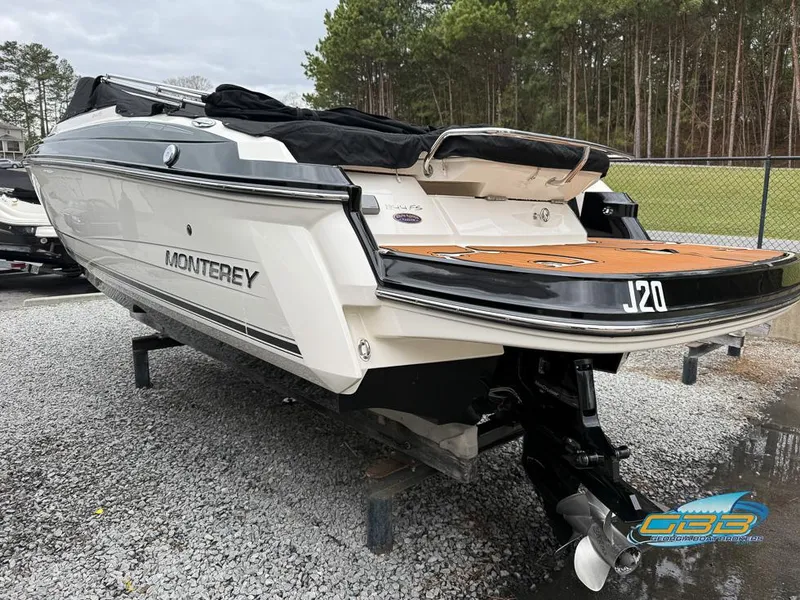 Slide: The Image of 2014 Monterey 244FS boat on gravel, rear view, with trees in background. - 2