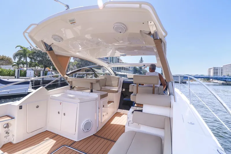 Slide: The Image of 2016 Pursuit SC 365i yacht interior with seating, docked by waterfront buildings. - 16