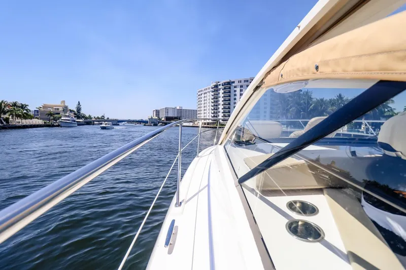 Slide: The Image of 2016 Pursuit SC 365i yacht cruising on a sunny waterway with cityscape views. - 5
