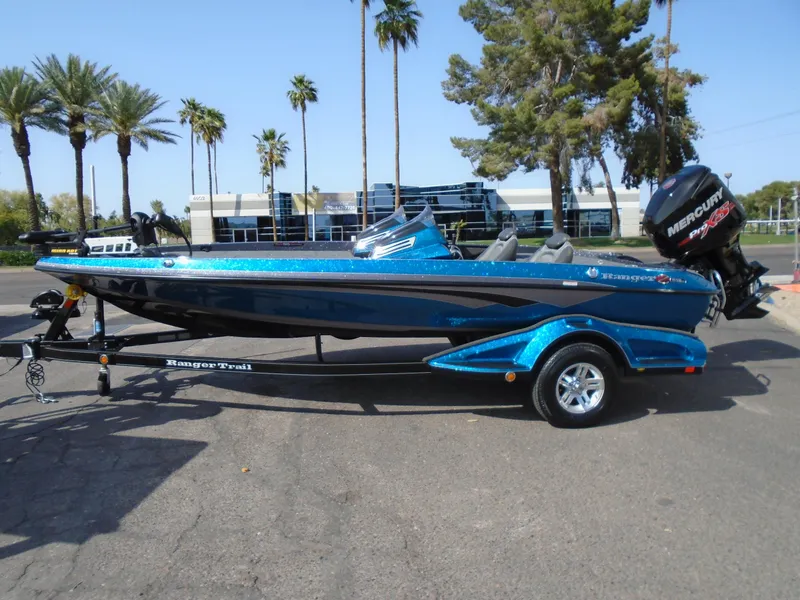 Slide: The Image of 2018 Ranger Z518 Comanche boat on trailer, parked outdoors with palm trees in the background. - 2