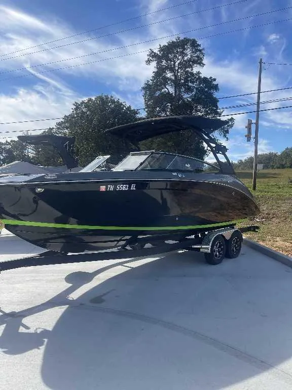Slide: The Image of 2021 Yamaha Boats 255X on trailer, sleek black design with green accent, parked outdoors. - 1
