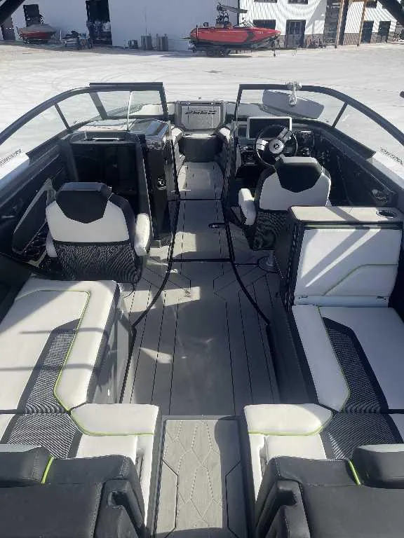 Slide: The Image of 2021 Yamaha Boats 255X interior with modern seating and steering wheel, docked outdoors. - 12