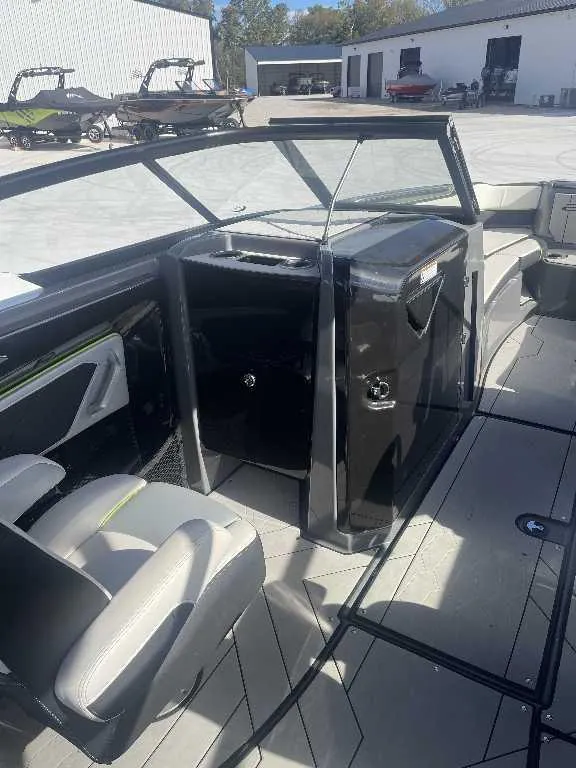 Slide: The Image of 2021 Yamaha Boats 255X interior with seating and dashboard, docked near other boats. - 9