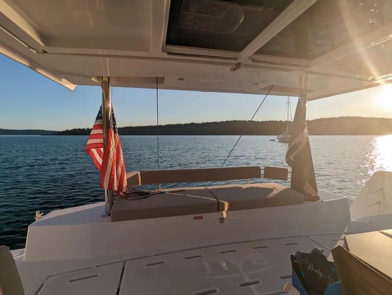 Slide: The Image of 2022 Bali 4.6 yacht on serene water at sunset with flags. - 16
