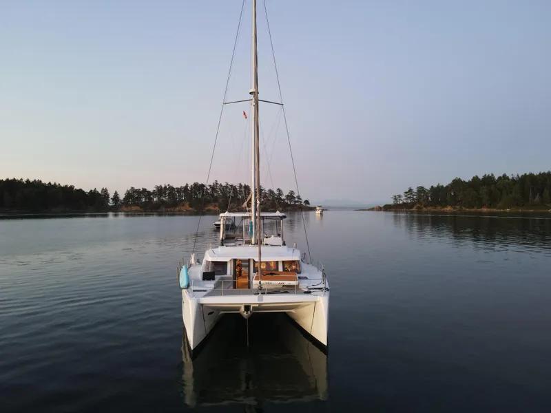 Slide: The Image of 2022 Bali 4.6 catamaran on calm water, surrounded by trees and serene landscape. - 46