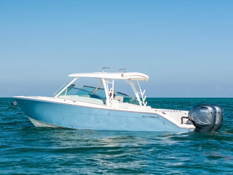 Slide: The Image of 2024 Cobia 330 Dual Console boat on open water, side view. - 0
