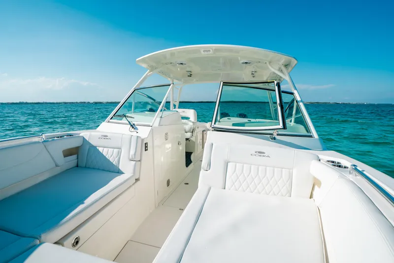 Slide: The Image of 2024 Cobia 330 Dual Console boat on clear blue water, showcasing spacious seating and sleek design. - 13