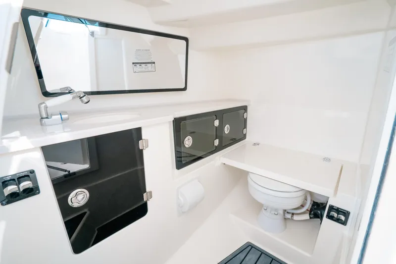 Slide: The Image of 2024 Cobia 330 Dual Console boat bathroom with sink, mirror, and storage cabinets. - 15
