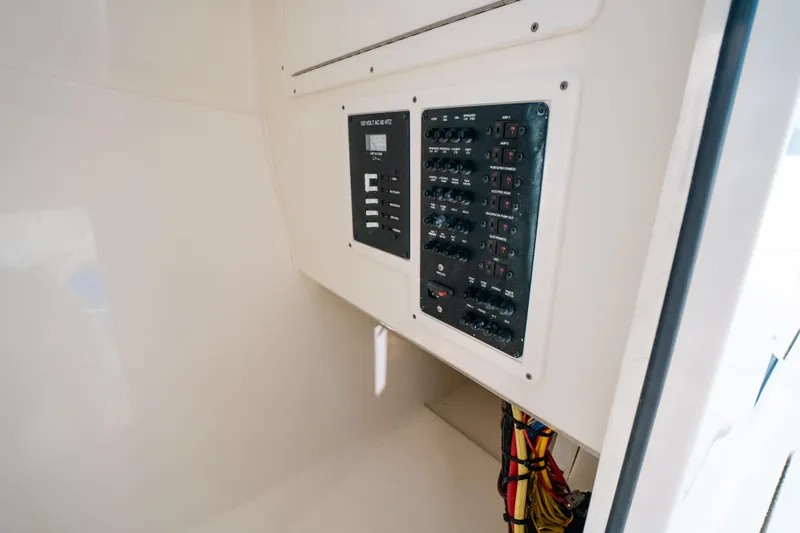 Slide: The Image of Electrical panel inside 2024 Cobia 330 Dual Console boat, showcasing wiring and controls. - 16